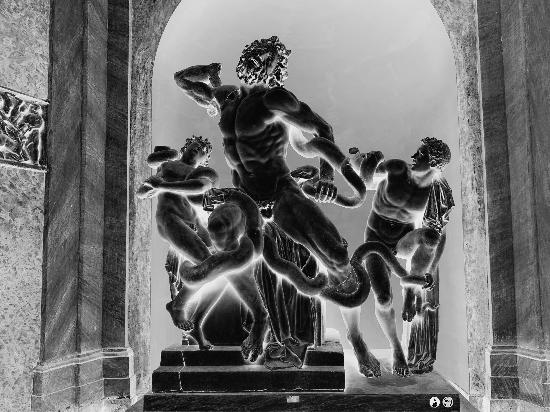 The Laocoön sculptural group displayed inside an arched niche, its figures appearing dark against glowing surroundings through color inversion.